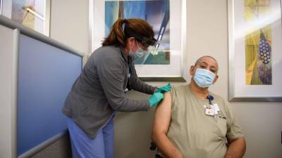 PITTSBURGH, PA - DECEMBER 17: Nurse Mary Catherine Klee injects a COVID-19 vaccine dose into Housekeeper Mecrecco Pogue, 68, at the Pittsburgh VA Medical Center on December 17, 2020 in Pittsburgh, Pennsylvania. The Pittsburgh VA Medical Center received a total of 975 initial doses of the vaccine to begin immunizing its frontline health workers and employees deemed most at-risk. Each employee immunized with the 1st dose will return in 21 days to receive the 2nd dose before complete immunization can be achieved. Jeff Swensen/Getty Images/AFP== FOR NEWSPAPERS, INTERNET, TELCOS & TELEVISION USE ONLY ==