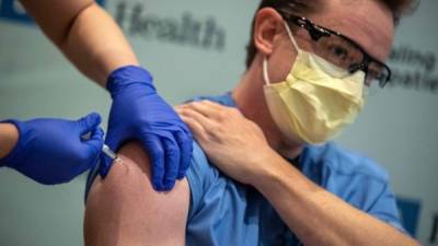 El especialista de terapia respiratoria de la UCLA, Matt Dartt, recibe la primera dosis de la vacuna de Pfizer en California./Foto referencial AFP.