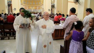 El padre Saturnino Senis rocía con agua bendita a los feligreses.
