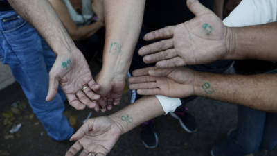 Con un marcador verde ponen los números en la muñeca a los venezolanos que van a comprar al mercado en San Cristóbal.