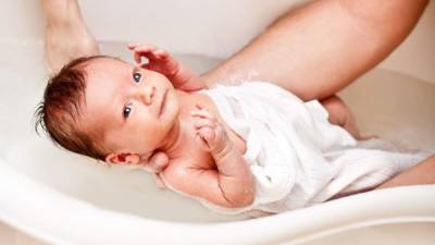 Small baby first bathing on father hands