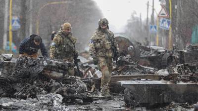 Militares ucranianos buscan artefactos explosivos en las calles de acceso a la capital.