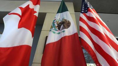 (FILES) This file photo taken on September 24, 2017 shows the Mexican, US and Canadian flags in the lobby where the third round of the NAFTA renegotiations took place in Ottawa, Ontario.Canada announced on January 23, 2018 it will sign on the Trans Pacific Partnership, moving to diversify its trade relationships as Canadian, US and Mexican negotiators kicked off a sixth round of talks on a 1994 free trade pact that Washington has threatened to dump. Canada had initially balked at joining the proposed TPP last year, acting as the main holdout in negotiations after US President Donald Trump decided in early 2017 to go it alone under his 'America First' policy. / AFP PHOTO / Lars Hagberg