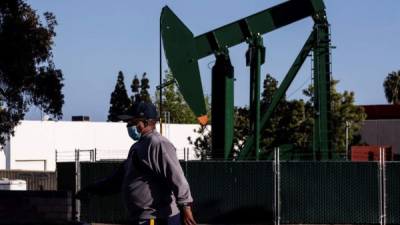 Un hombre con una máscara facial pasa frente a un pumpjack funcionando en medio de la pandemia de coronavirus en Signal Hill, California, EE. UU., 21 de abril de 2020. EFE / EPA / ETIENNE LAURENT