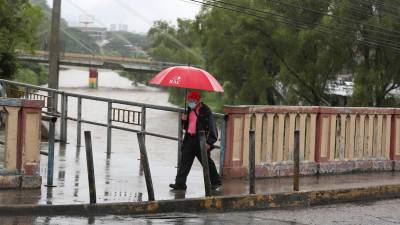 Un ciudadano camina mientras al fondo se ve el elevado nivel del río Choluteca, en Tegucigalpa (Honduras), en una fotografía de archivo. EFE/Gustavo Amador