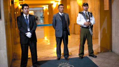 Security guards watch mourners gathered outside the funeral home where the body of murdered Argentinean artist Facundo Cabral outside lays in Guatemala City, Saturday, July 9, 2011. One of Latin America's most admired folk singers, Facundo Cabral, was killed Saturday when three carloads of gunmen ambushed the vehicle in which he was riding, prompting expressions of anguish from across the region. Authorities said the performer's concert promoter was apparently the target. (AP Photo/Rodrigo Abd)