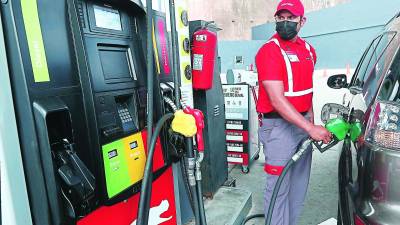 Un bombero de una estación de gasolina llena el tanque de combustible de un carro.