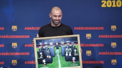 TOPSHOT - Barcelona's Argentinian defender Javier Mascherano poses with a framed picture of him and the major trophies he won with the football club during a farewell ceremony in Barcelona ahead of his transfer to China on January 24, 2018.Mascherano was unveiled as the latest big name to move to China, signing for Hebei China Fortune from Barcelona. / AFP PHOTO / LLUIS GENE