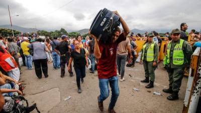 Los venezolanos caminan frente a los oficiales de la Guardia Nacional mientras cruzan el puente internacional Simón Bolívar, en Cúcuta, Colombia. AFP