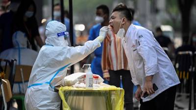 A health worker takes a swab sample from a man to be tested for the Covid-19 coronavirus at a makeshift testing site outside a shopping mall in Beijing on June 15, 2022. (Photo by Jade GAO / AFP)