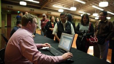 Un trabajador registra demandantes de empleo durante una feria de trabajo en un parque temático de California . AFP