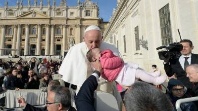 Foto tomada este 27 de noviembre de 2019 en el Vaticano que muestra al papa Francisco besando a un niño cuando llega a la audiencia general semanal en la Plaza de San Pedro en el Vaticano.