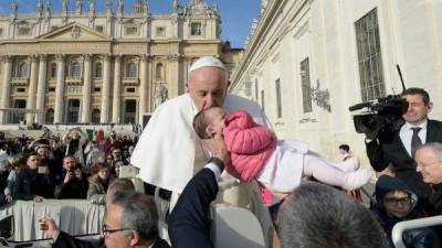 Foto tomada este 27 de noviembre de 2019 en el Vaticano que muestra al papa Francisco besando a un niño cuando llega a la audiencia general semanal en la Plaza de San Pedro en el Vaticano.