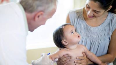 A baby girl with her mother at an appointment with a doctor getting her immunization, vaccines, and shots.
