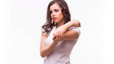 Acute pain in a woman elbow. Female is holding hand to spot of elbow pain indicating location of the pain. Isolation on a white background.