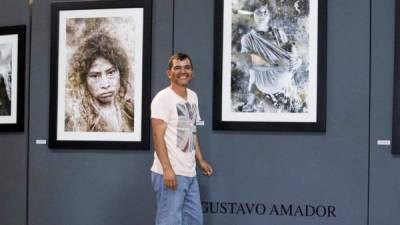 El fotógrafo hondureño Gustavo Amador posa frente a sus obras. EFE