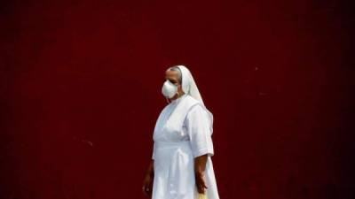 Una monja con tapabocas fue registrada este miércoles al pasar frente al templo de la Parroquia de Nuestro Señor de Candelaria, en Ciudad de Guatemala (Guatemala). EFE/Esteban Biba