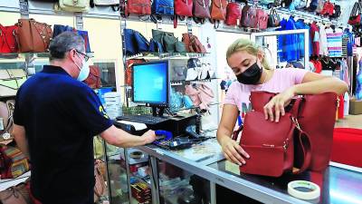 Un microempresario vende una cartera a una cliente en su tienda de ropa y accesorios.