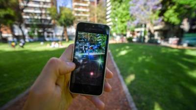 Buenos Aires, Argentina - November 11, 2016: Apple iPhone 5c held in one hand showing its screen with Pokemon Go application. Park on the background.