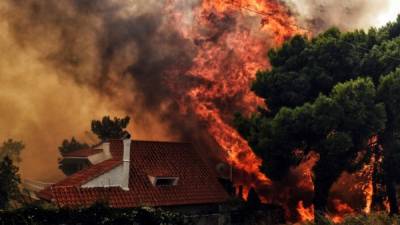 A house is threatened by a huge blaze during a wildfire in Kineta, near Athens, on July 23, 2018.More than 300 firefighters, five aircraft and two helicopters have been mobilised to tackle the 'extremely difficult' situation due to strong gusts of wind, Athens fire chief Achille Tzouvaras said. / AFP PHOTO / VALERIE GACHE