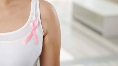 Cropped image of woman wearing pink ribbon, symbol of breast cancer awareness