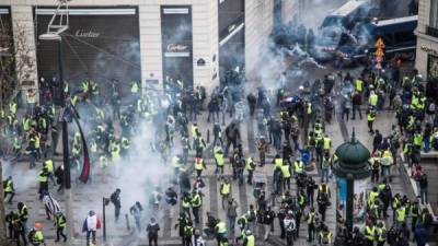 Chalecos amarillos se enfrentan a las fuerzas policiales durante una manifestación cerca de los Campos Elíseos en París. EFE