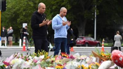 Dos hombres rezan hoy en un memorial de flores cerca de Al Noor Masjid en Deans Rd en Christchurch, Nueva Zelanda. EFE