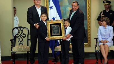 Marlon Escoto junto a dos escolares de occidente entregaron la placa a Lobo.