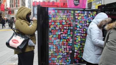 Varias personas escriben sus deseos para el año nuevo en papeles que colgarán en un muro de deseos (Wish Wall) ayer viernes 29 de diciembre de 2017, en Times Square en Nueva York, EUA). EFE