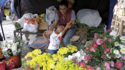 AME1711. TEGUCIGALPA (HONDURAS), 11/05/2019.- La campesina Rudis Laínez y su hija en su puesto de flores este 11 de mayo de 2019 en Tegucigalpa (Honduras). En Honduras más de 700.000 madres solteras sostienen el 33 por ciento de los hogares del país, informó este sábado el Comisionado Nacional de los Derechos Humanos (CONADEH), en la víspera del 'Día de la madre', que se conmemora mañana. EFE/Gustavo Amador