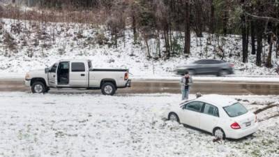 Un hombre auxilia a un conductor que se salió de la autopista congelada debido a la tormenta de nieve en Carolina del Norte./AFP.