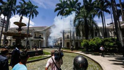 Un grupo de personas observa el humo de fuegos pirotécnicos arrojados por manifestantes al interior de la sede de la Asamblea Nacional el 5 de julio de 2017, en Caracas (Venezuela). EFE