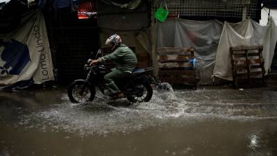 Un motociclista transita por una calle inundada en el centro de San Salvador, en una fotografía de archivo.