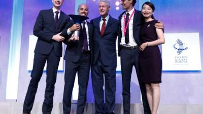 Prudot, sostiene el trofeo en sus manos, junto a los miembros de su equipo y el expresidente Bill Clinton.