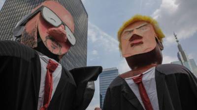 TOPSHOT - Protestors carry models of US President Donald Trump (R) and Belgium's Prime Minister Charles Michel (L) they take part in a rally in Brussels on July 7, 2018, against the forthcoming NATO summit and scheduled visit of US President Donald Trump on July 11 and12. / AFP PHOTO / Aris Oikonomou