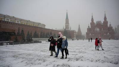 Un grupo de personas visitan la plaza roja de Moscú pese a fuertes nevadas.