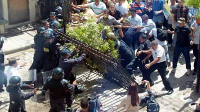 Momento en el que los manifestantes botaron el portón para sacar al periodista David Romero del juicio. Foto de archivo.