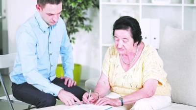 Un operario de banca ayuda a una jubilada a llenar una solicitud.