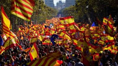 Los manifestantes ondean banderas Senyera españolas y catalanas durante una manifestación a favor de la unidad en Barcelona.