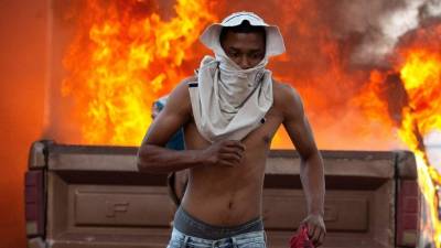 Una persona corre durante enfrentamientos entre antichavistas y miembros de la Guardia Nacional Bolivariana de Venezuela este sábado en el paso fronterizo ubicado en la localidad de Pacaraima (Brasil), en el límite fronterizo entre Brasil y Venezuela. EFE