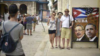 Turistas posan junto a un rótulo en la entrada de un restaurante con la imagen de Raúl Castro y Barack Obama. AFP