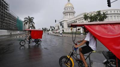 Un par de bicitaxis captados en julio frente al Capitolio de La Habana (Cuba). EFE/Ernesto Mastrascusa.