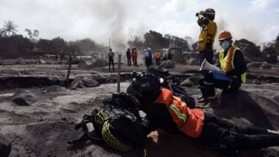 Rescuers from Mexico and Salvador take part in the search for victims of the Fuego Volcano eruption, in the ash-covered village of San Miguel Los Lotes, in Escuintla Department, about 35 km southwest of Guatemala City, on June 11, 2018.A week after Guatemala's Fuego volcano eruption the death toll has reached 110, leaving dozens of people injured, more than 12,000 evacuated and some 4,500 with no homes to return to, according to figures from the country's disaster agency. / AFP PHOTO / Johan ORDONEZ