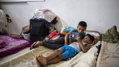 A pair of migrant boys watch a video on a tablet at a migrant shelter on May 26, 2021 in Matamoros, Mexico. - Once, Abraham Barberi was known as the 'pastor of rappers,' host of Christian hip hop concerts targeting young drug dealers in Mexico in hopes of putting them on a different path. Now, he is making headlines by caring for a new flock: more than 200 people from Central and South America who dream of crossing the Rio Grande and migrating to the United States. (Photo by Sergio FLORES / AFP)