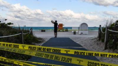 A tourist trespasses at the closed Miami Beach in Miami, on March 19, 2020. - The Miami Beach mayor, Dan Gelber, warned of 'devastating consequences' over the virus and ordered bars and gyms to close this week, telling springbreakers: 'You've got to think about the person next to you and even the person you don't know.' (Photo by CHANDAN KHANNA / AFP)