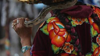 Bailarines de la Danza de Mexicanos sostenían ayer serpientes durante una presentación en las calles del municipio de Chichicastenango, Quiché, en las festividades de la feria patronal en honor a Santo Tomás. EFE.