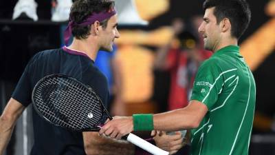 Serbia's Novak Djokovic (R) shakes hands with Switzerland's Roger Federer at the end of their men's singles semi-final match on day eleven of the Australian Open tennis tournament in Melbourne on January 30, 2020. (Photo by Greg Wood / AFP) / IMAGE RESTRICTED TO EDITORIAL USE - STRICTLY NO COMMERCIAL USE