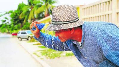 Un ciudadano echándose agua para refrescarse.