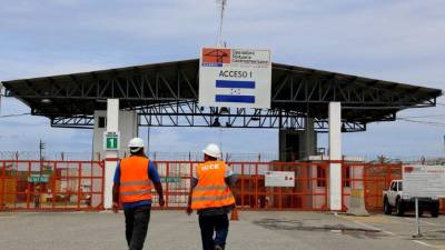 Dos empleados caminan hacia la entrada de la OPC en Puerto Cortés.