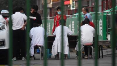Funcionarios de salud frente a un mercado de Pekín. Las autoridades cerraron al menos dos esrablecimientos de esta clase por sospecha de contaminación por coronavirus.